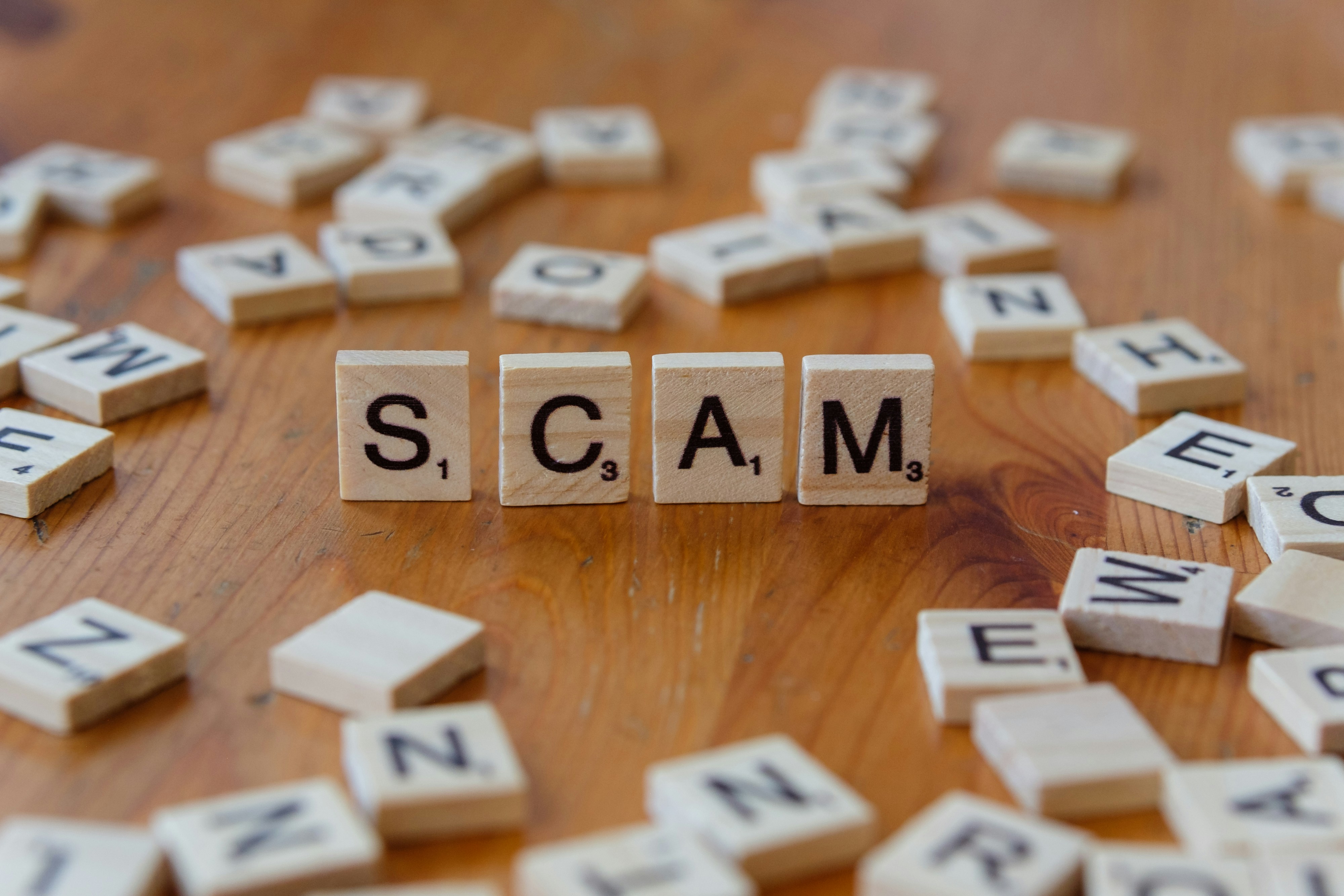 The word scam spelled in letter tiles
